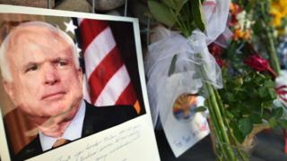 Фотография Джона Маккейна сидит с цветами возле офиса покойного сенатора в Фениксе.