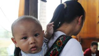 Bebê chinês nas costas de sua mãe