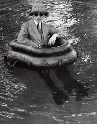 A man in a suit sits in a rubber ring in open water