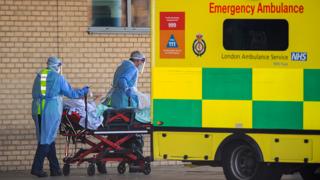 NHS workers in PPE take a patient with an unknown condition to an ambulance at Queens Hospital in London - 21 April 2020