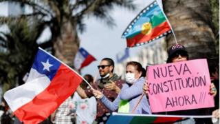 Manifestantes sostienen banderas y carteles