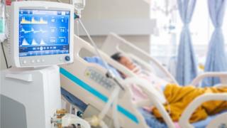 person on ventilator in hospital bed