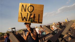 American activists hold signs at the border between the US and Mexico during a protest against the new construction plan of a steel wall between Santa Teresa, New Mexico, and Ejido San Jeronimo, in the municipality of Juarez, Chihuahua state, Mexico, on June 2, 2018 in Ciudad Juarez.