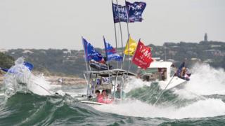 A boat is engulfed in waves from the large wakes of a flotilla of supporters of US President Donald Trump