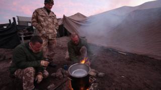 Soldiers cooking rations over a stove