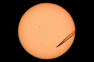 A jet airliner leaves a vapour trail as the planet Mercury is seen, lower left quadrant, transiting across the face of the sun in Las Vegas, Nevada