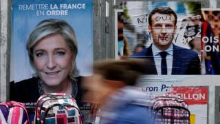 Женщина проходит мимо официальных плакатов кандидатов на президентских выборах во Франции 2017 года