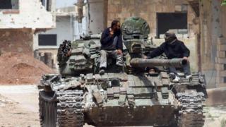 Un tanque de guerra recorriendo una calle polvorienta