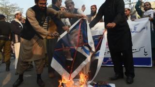 Пакистанские демонстранты сжигают изображения президента США Дональда Трампа и американского флага во время акции протеста против сокращения помощи США в Лахоре 5 января 2018 года.