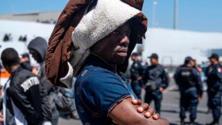 Africa's top shots: 5-11 July 2019 11 A man part group of asylum seekers, mostly from African countries, waits for a negotiation commission to walk out El Chaparral port of entry during a protest in Tijuana, Baja California state on July 9, 2019, northwestern Mexico. - Asylum seekers claimed that Mexican migration officers were selling spots on the line to get an interview with US migration authorities.