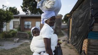 A mother carrying a bag on her head and a baby on her back - Saturday 11 May