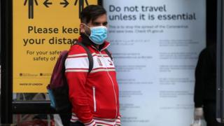 Commuter catching a bus wearing a face mask on 11 May