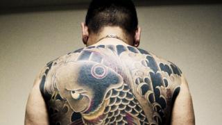 Hombre con tatuajes en su espalda