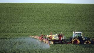 Фермер распыляет химическое удобрение на своем пшеничном поле во Франции