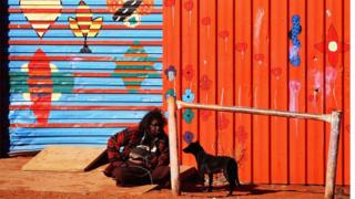 Женщина-абориген сидит на земле в отдаленном городе в региональной Австралии