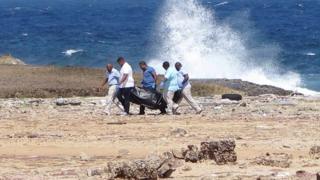 Médicos forenses cargan el cuerpo de uno de los fallecidos tras el accidente.,