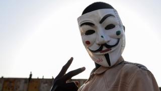 A Sudanese protester wears a Guy Fawkes mask outside the army headquarters in Khartoum on May 6, 2019. - Defiant Sudanese protesters broke their fast on the first day of Ramadan today with chicken soup and beans, vowing to press on with their campaign for a civilian rule. As the call for the evening Maghreb prayer echoed, crowds of protesters gathered at the sit-in area in central Khartoum for iftar after a day of sweltering heat, an AFP correspondent reported.