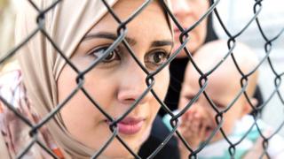 امرأة تنظر خلال حاجز حديدي
