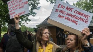 Two women hold signs at an anti-lockdown protest