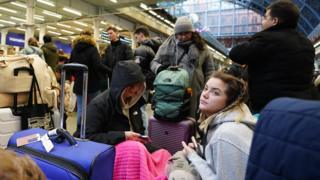 Passengers sit on the floor of the concourse at the entrance to Eurostar in St Pancras International station,
