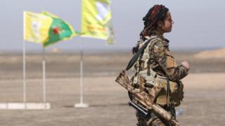 Боец сирийских демократических сил (SDF) стоит с ее оружием