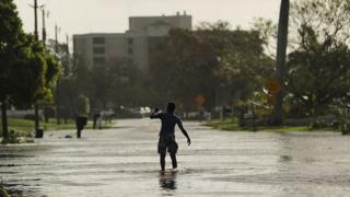 Подросток гуляет по затопленным улицам на следующее утро после того, как 11 сентября 2017 года в Неаполе, Флорида пронесся ураган Ирма