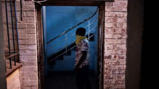 A foreign migrant wears a bandana as he leaves a building in the Kwa Mai Mai area in Johannesburg, on May 10, 2020.