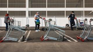 Die Leute stehen vor dem Supermarkt an