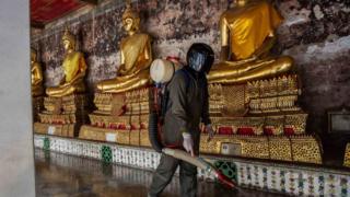 A person in protective clothing disinfects a Buddhist temple in Bangkok