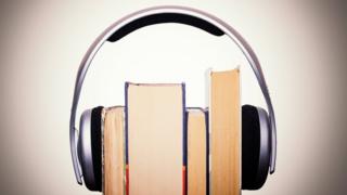 Livros envolvidos por um fone de ouvido