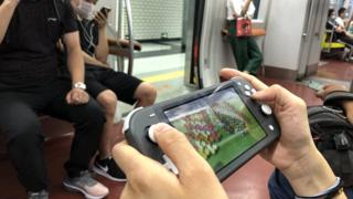 A passenger uses a Nintendo Switch to play video game 'Animal Crossing: New Horizons' on a subway train of Beijing Subway Line 1 on June 14, 2020 in Beijing, China.