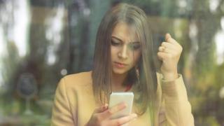 Mujer molesta mirando el celular.