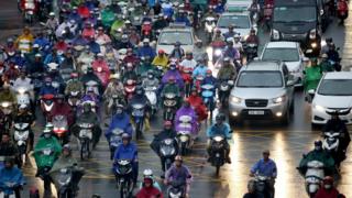 Dozens of motorbikes wait in a traffic jam in the rain in Hanoi, June 2017