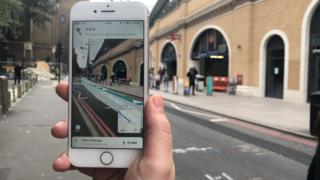 Смартфон показывает улицу с наложенными цифровыми направлениями