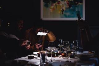 Two men take photos of the their food in a restaurant