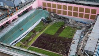rescue workers (orange suits, L) inspect a sports centre after its roof collapsed at the City University in Hong Kong