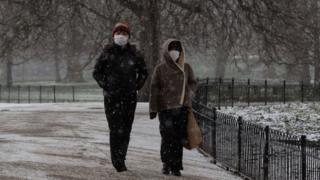 People walk in a snowy park in London