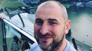 Vladimir Anikeev smiles at the camera on the top of a building overlooking Marina Bay in Singapore