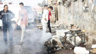 People gather at the site of suicide blasts in Baghda's Sadr City