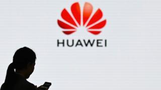 A woman in front of the Huawei logo