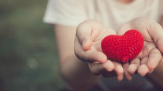 Manos abiertas con un corazón de lana