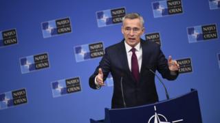 Jens Stoltenberg standing at a podium giving a speech