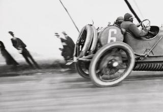 A racing car zooms past spectators