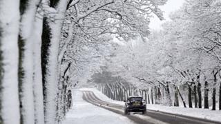 A car drives through a snowy scene near Birkenhead