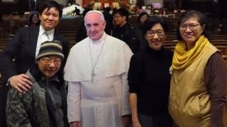 In Taiwan, people pose for pictures with a cardboard cutout of Pope Francis in the Catholic Holy Family Church in Taipei