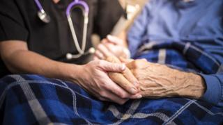 Foto de duas pessoas segurando mãos de uma das outras em um hospital
