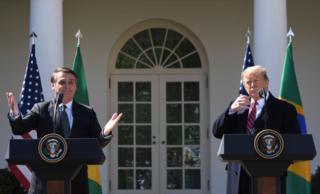 Imagem mostra Bolsonaro, à esquerda, e Donald Trump em discurso na Casa Branca
