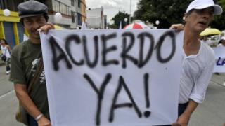 Men hold a banner reading "Agreement Now!" during a march for peace through streets of Cali, Colombia, on October 9, 2016