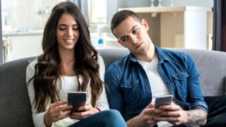 Pareja joven con sus celulares.