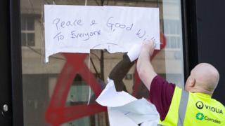 A council worker cleans the graffiti off a shop window in Belsize Park, North London